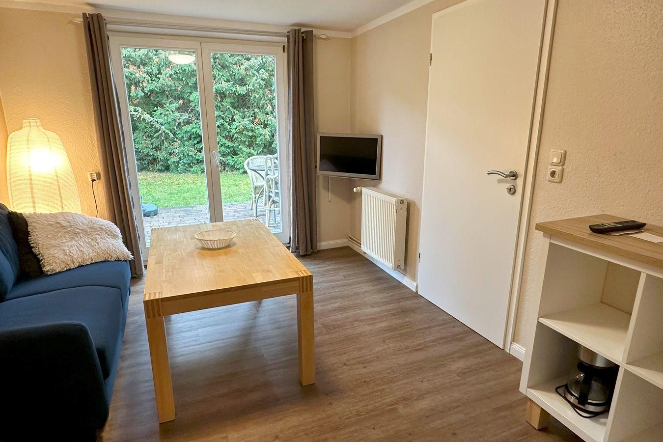 Wohnzimmer mit Couch, TV und Zugang zur eigenen Terrasse