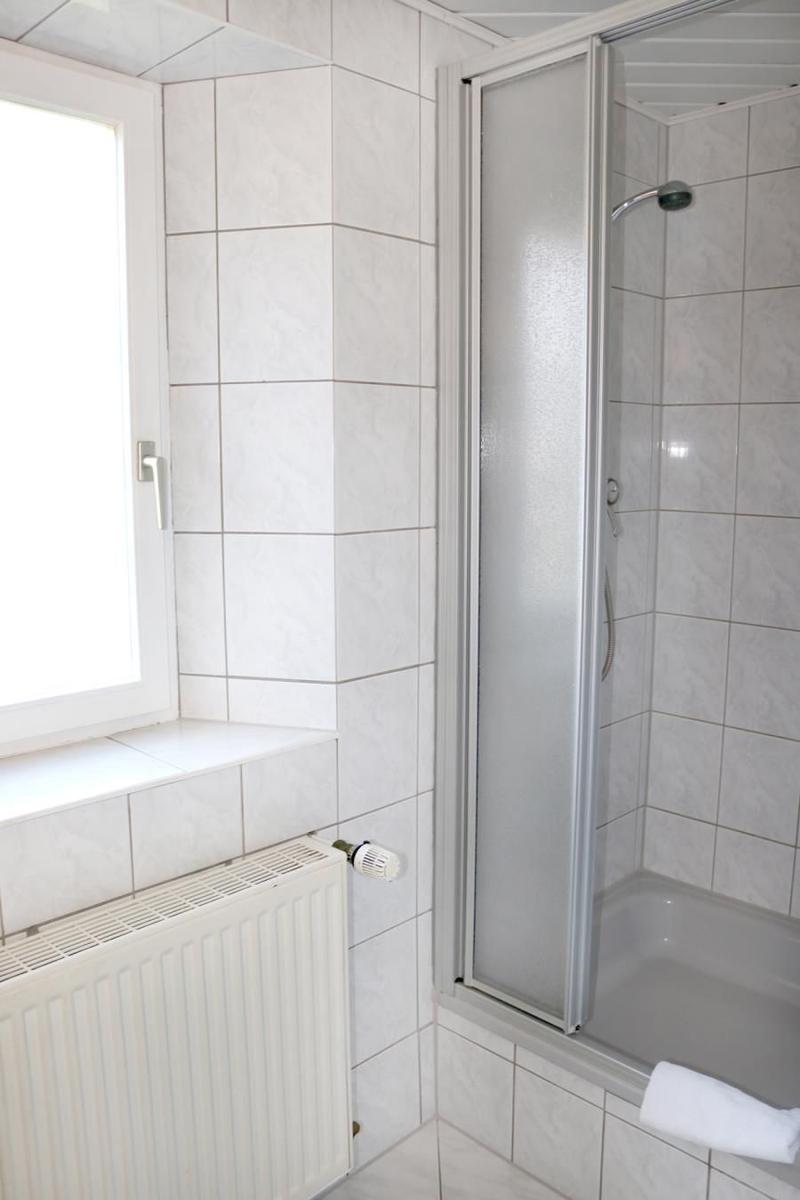 Badezimmer mit Dusche, Fenster und Heizkörper