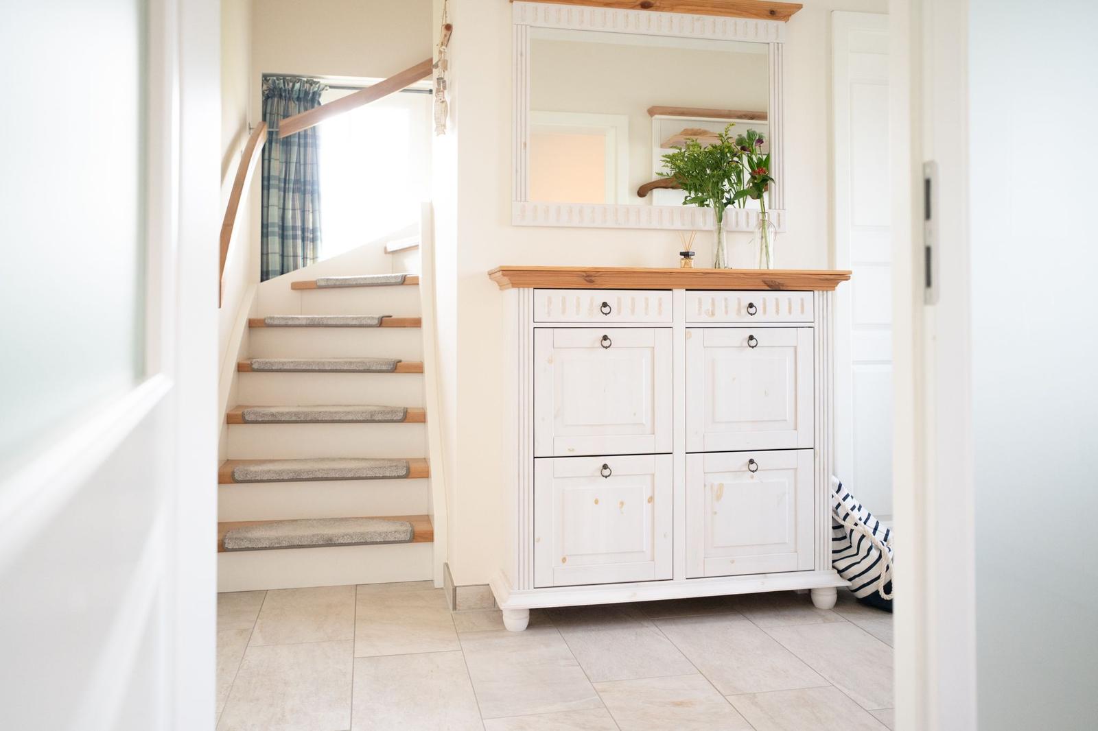 Eingangsbereich mit Schrank, Spiegel und Treppe.