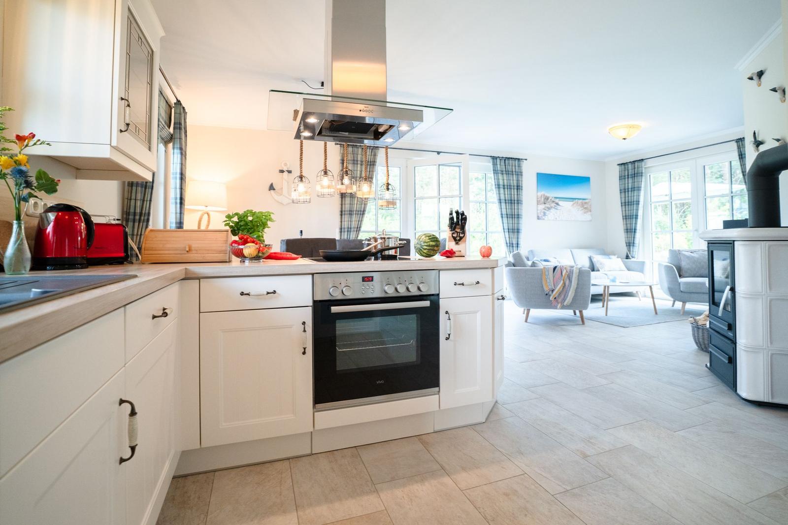 Küche mit weißer Einbauküche und Blick in Wohnzimmer mit Sofa und Kamin.