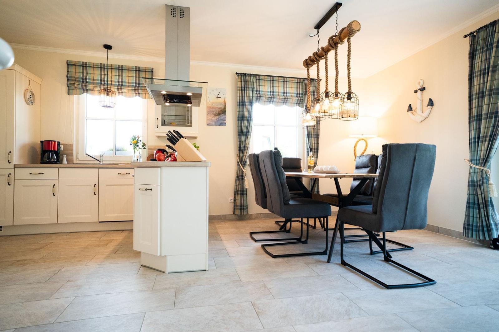 Küche und Essbereich mit Tisch, Stühlen und Plaidvorhängen.