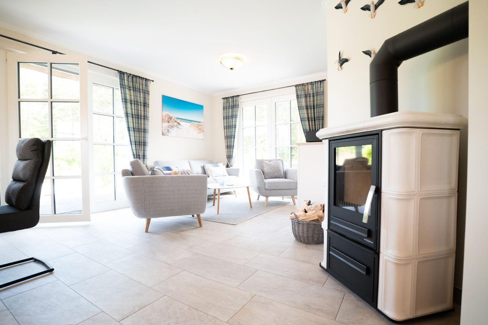 Wohnzimmer mit Kamin, Sitzgelegenheiten und Fenstern zum Ausblick.