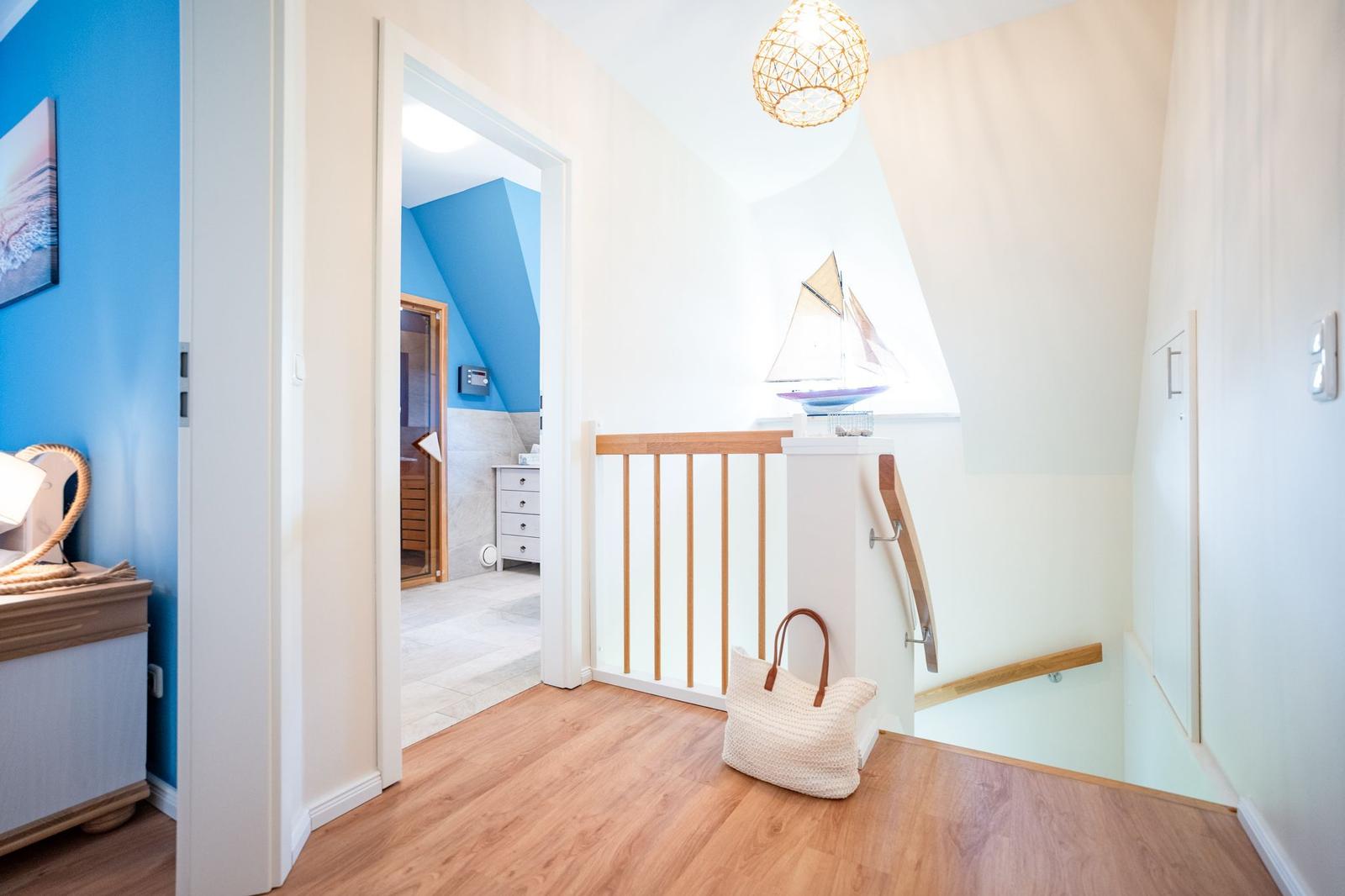 Flur mit Holzboden, Treppe und Blick in Sauna und Schlafzimmer.