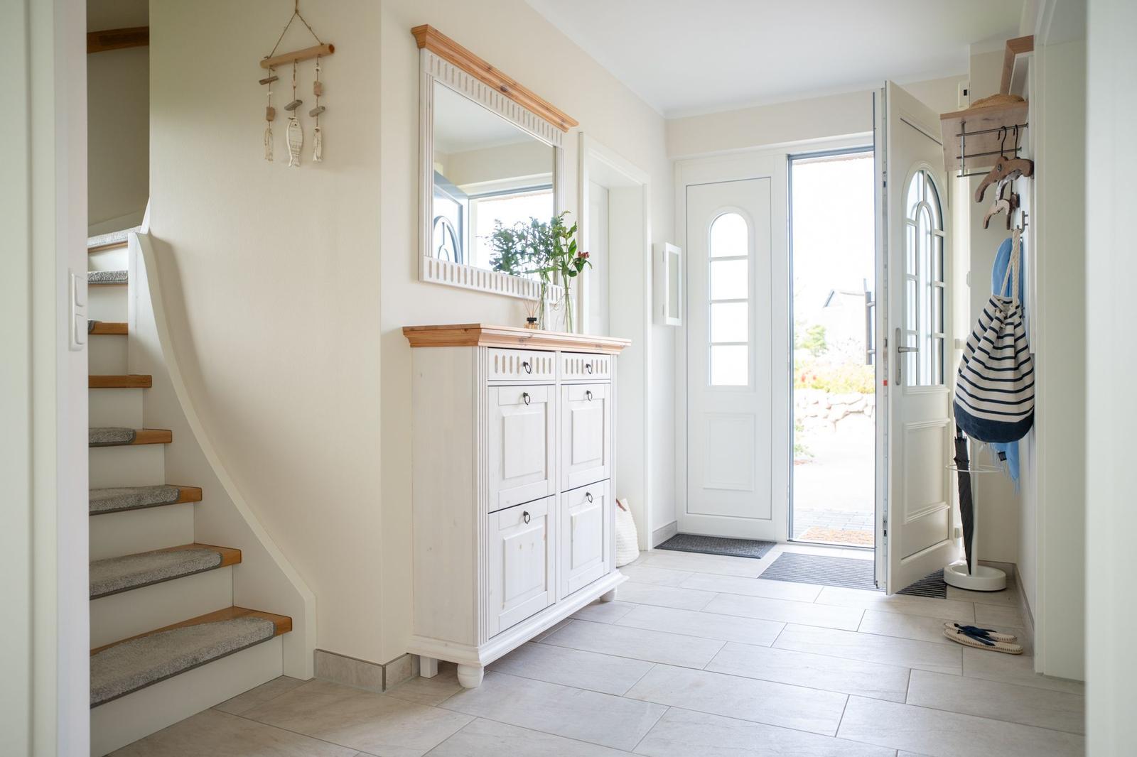 Eingangsbereich mit Garderobe, Spiegel und Treppe zur oberen Etage.