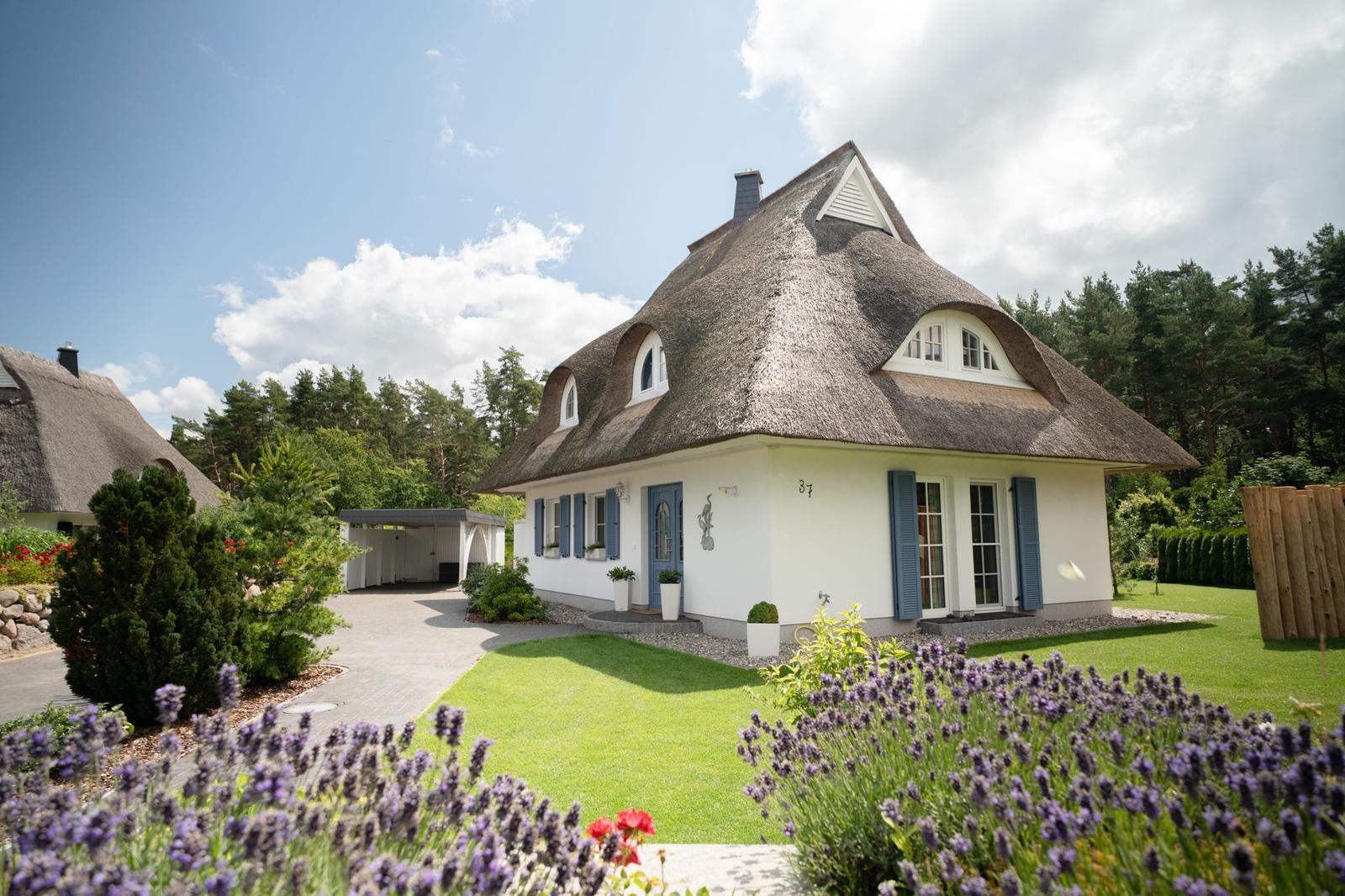 Haus mit Strohdach, blauen Fensterläden und gepflegtem Garten mit Lavendel.