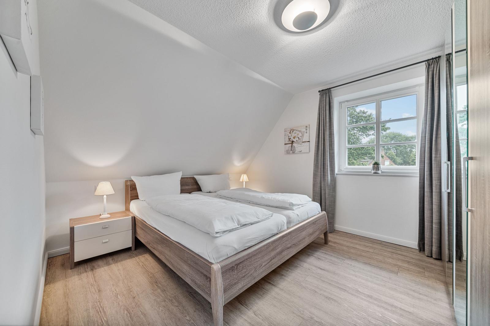 Schlafzimmer mit Doppelbett, Nachttisch und Fenster mit Blick.