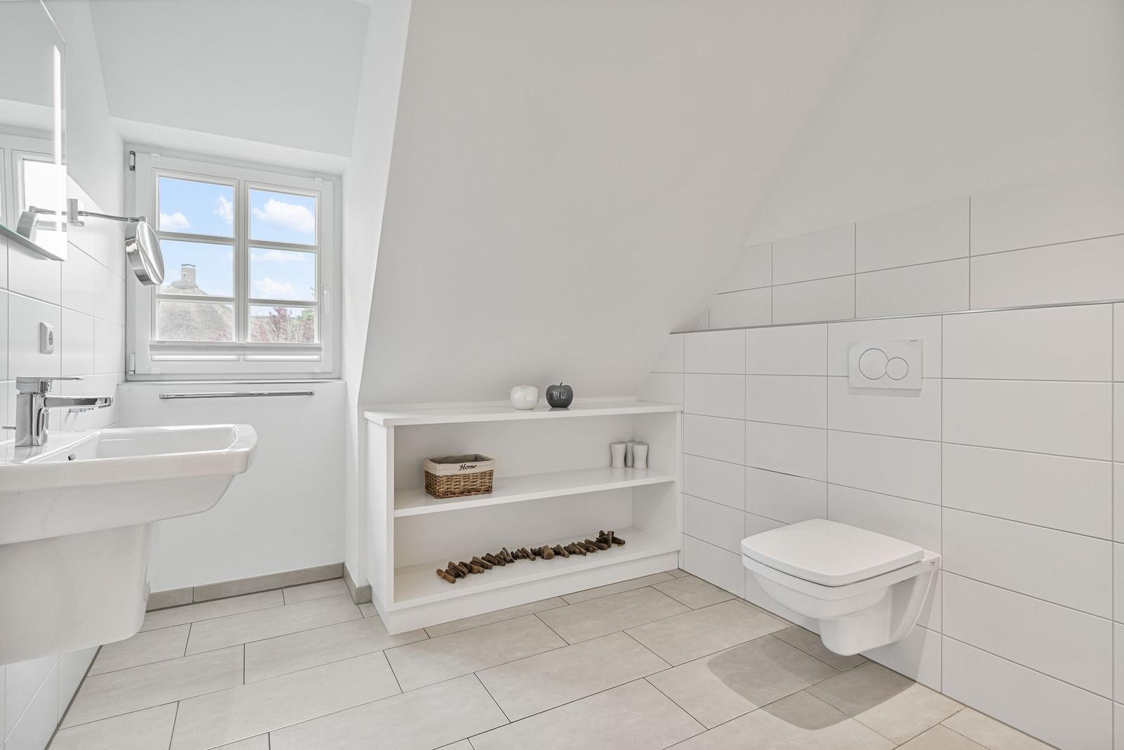 Badezimmer mit Fenster, Waschbecken, Toilette und Regal