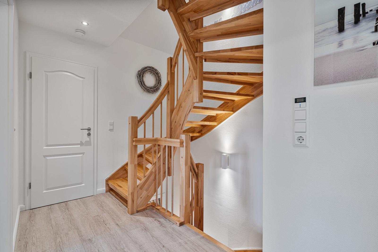Holztreppenhaus mit Eingangstür und Wandbild.
