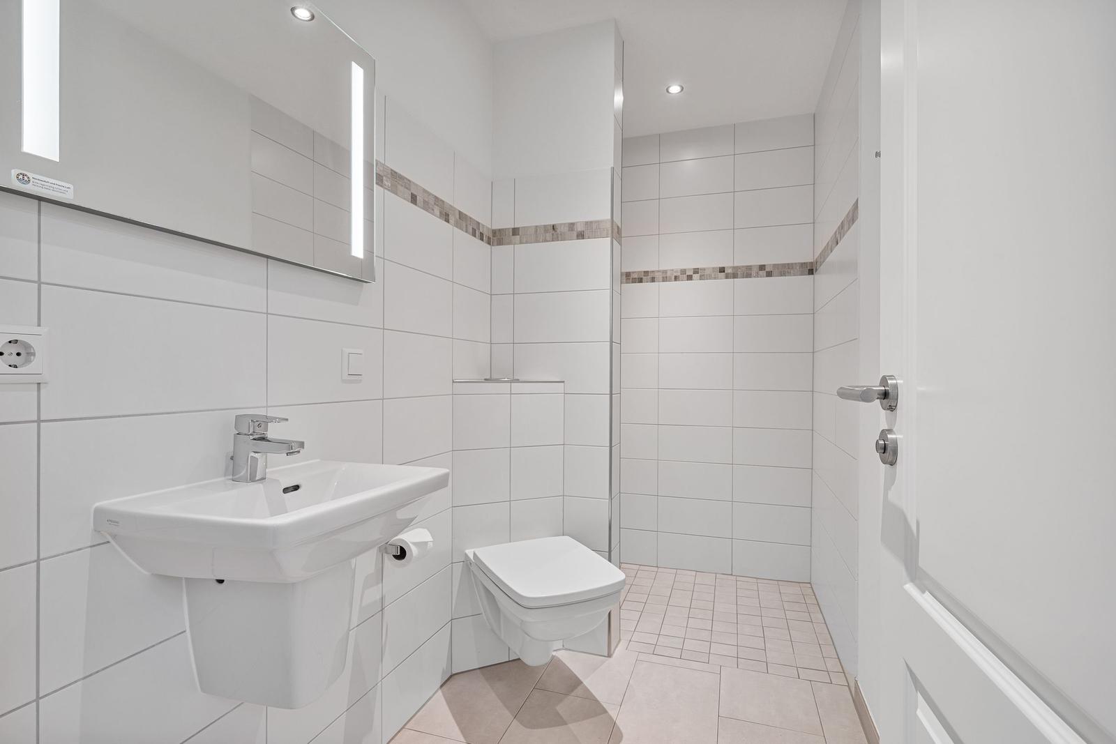 Badezimmer mit Waschbecken, Spiegel und Toilette.