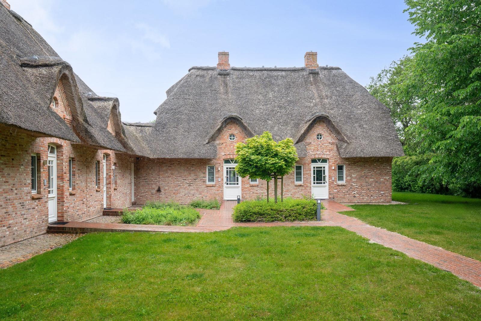 Rotes Backsteinhaus mit Strohdach und gepflegtem Garten