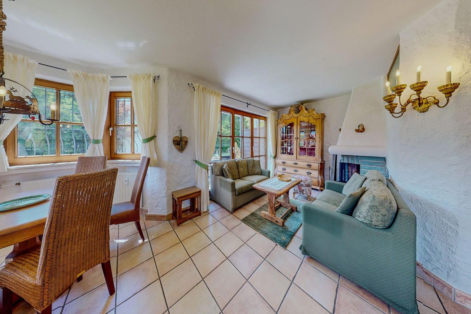 Wohn- und Essbereich mit Sofa, Tisch und Fenstern.