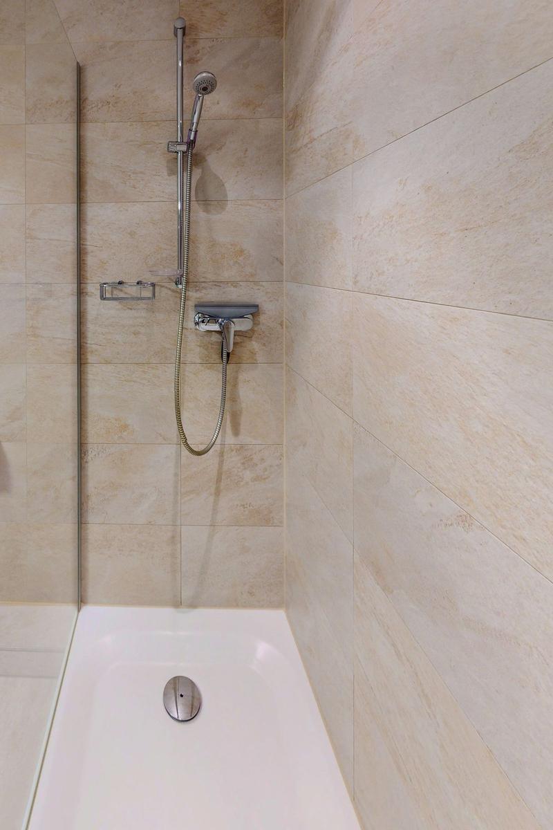 Dusche mit Handbrause und bodengleicher Badewanne.