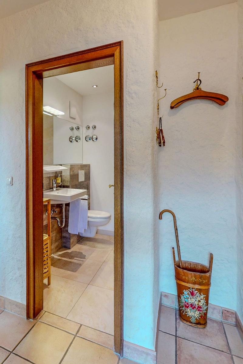 Badezimmer mit Waschbecken und Toilette. Holzrahmen und bemalter Eimer.