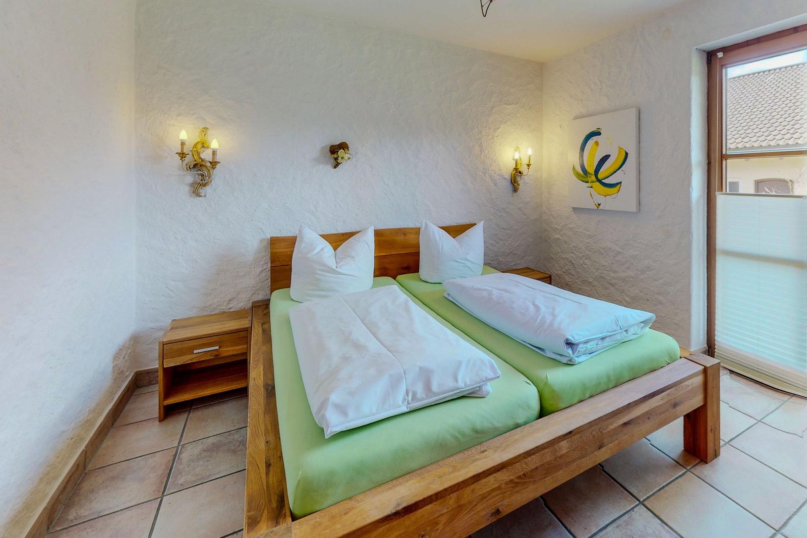 Zimmer mit Doppelbett, Holzgestell, grünen Matratzen und zwei Nachttischen.