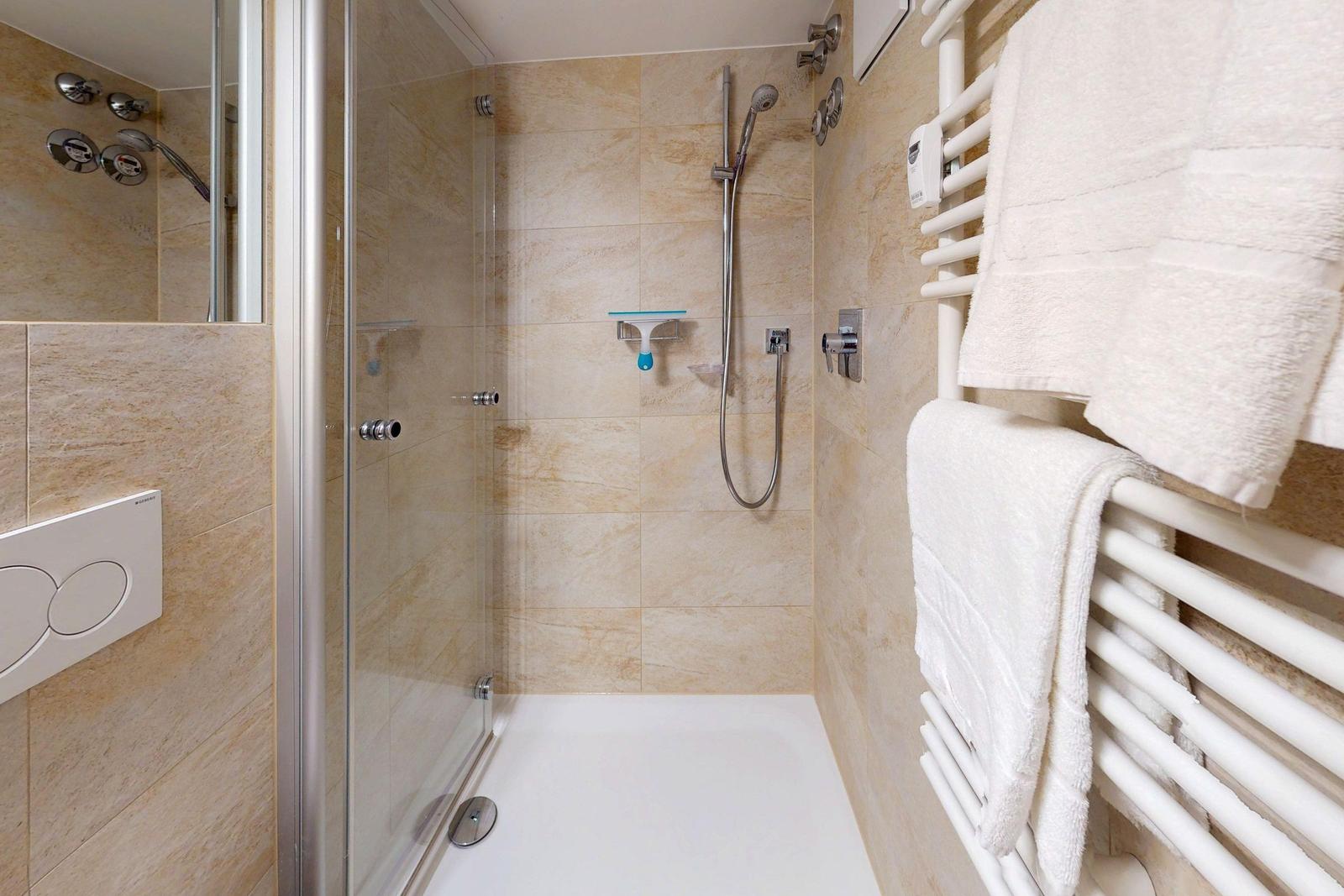 Duschkabine mit Duschbrause, Handtuchhalter und Heizkörper.