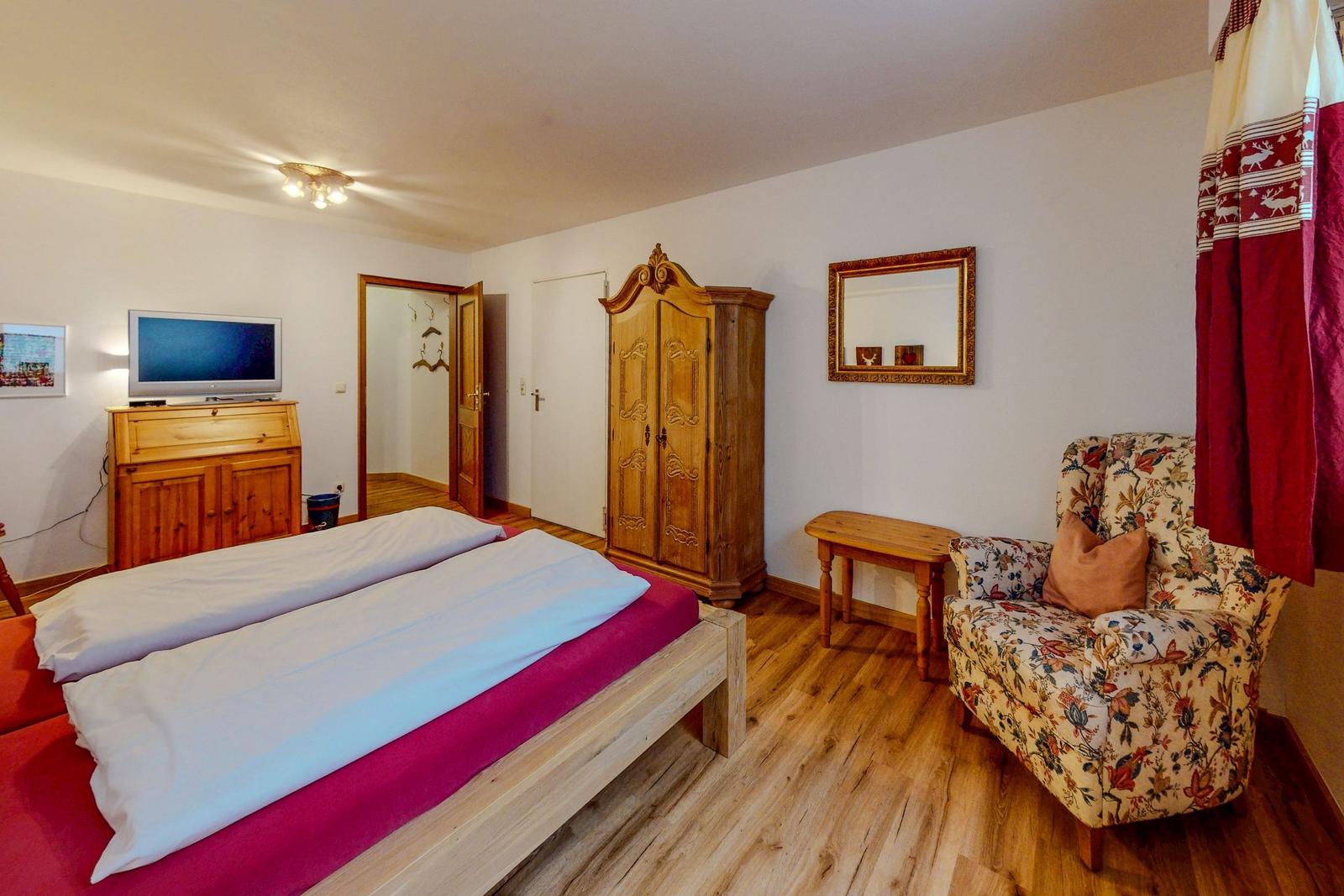 Schlafzimmer mit Bett, Kleiderschrank und Sessel.