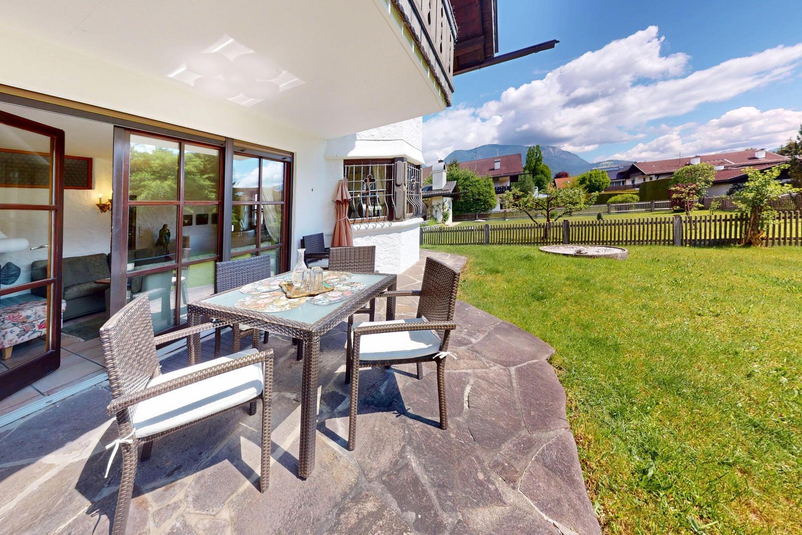 Terrasse mit Sitzgruppe, Garten und Bergblick.