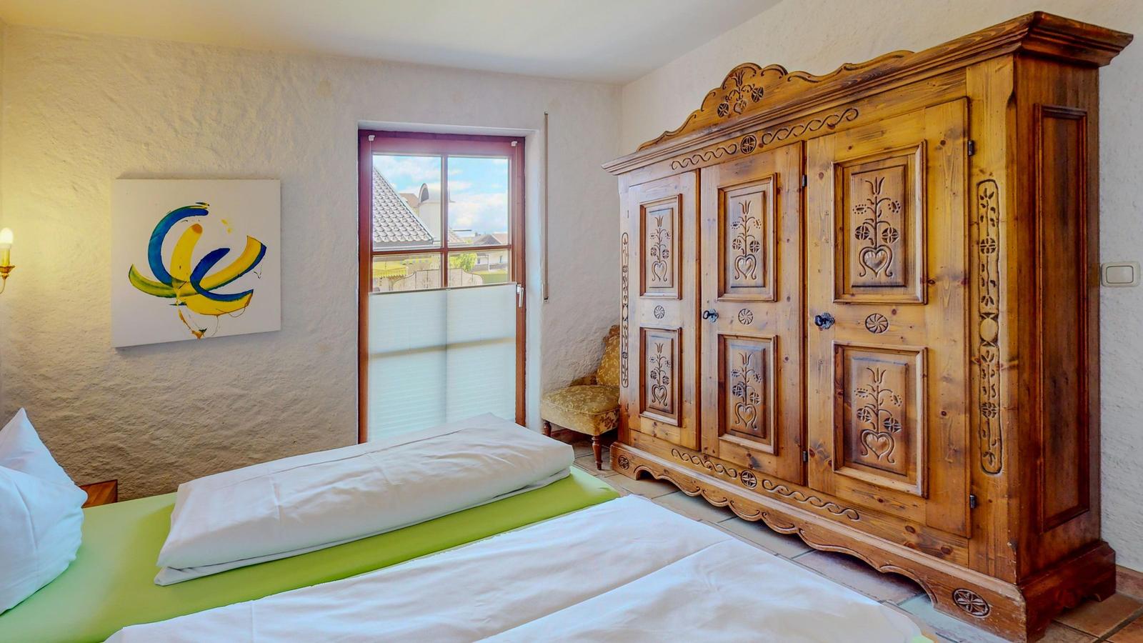 Schlafzimmer mit Bett, Holzschrank und Fensterblick.