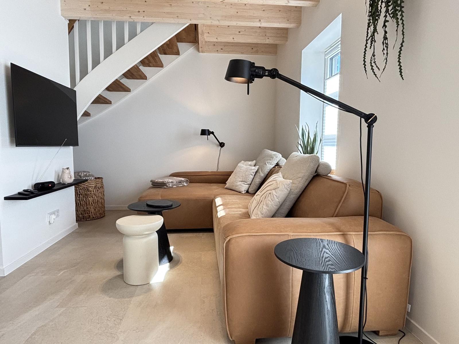 Wohnzimmer mit Sofa, Stehlampe und TV an der Wand.