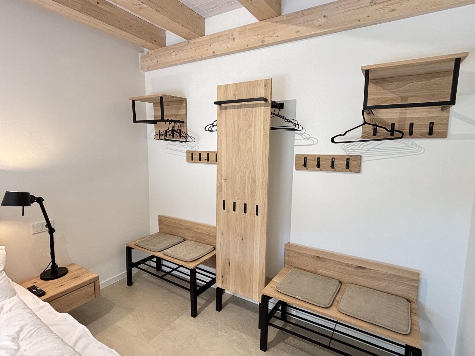 Schlafzimmer mit Kleiderschrank, Bänken und Hakenwand.