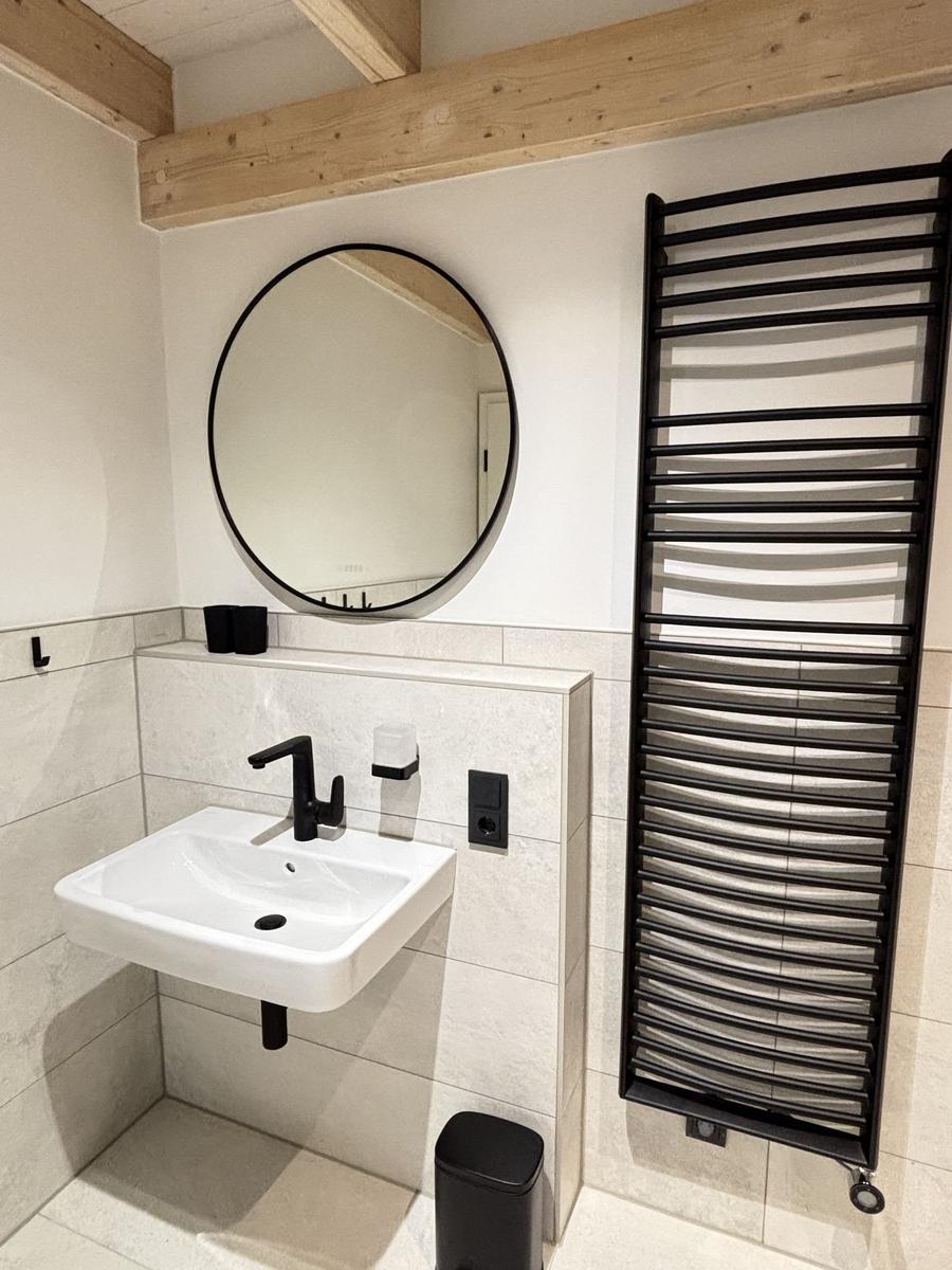 Badezimmer mit Waschbecken, Spiegel und Heizkörper
