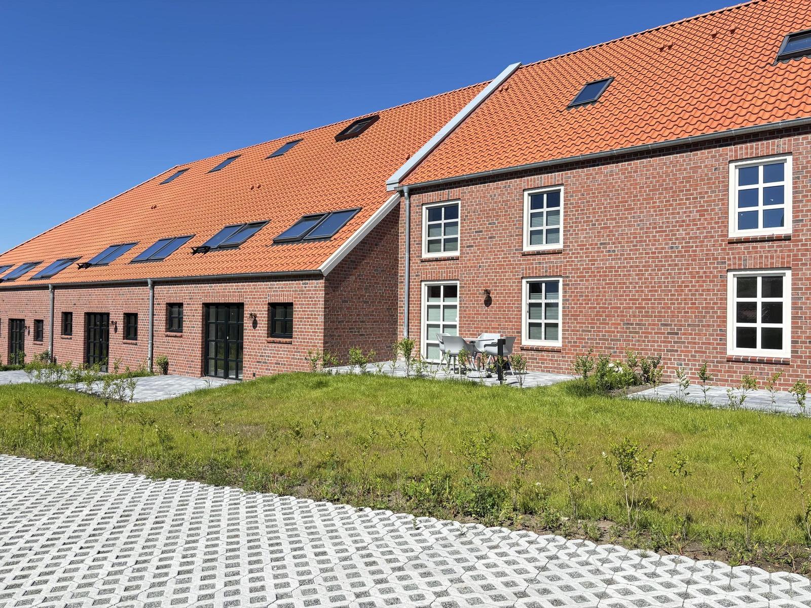 Rotes Ziegeldach mit Dachfenstern und Terrasse mit Garten.