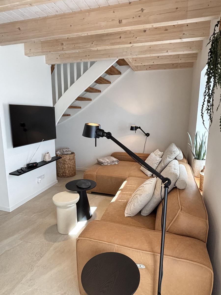 Wohnzimmer mit Sofa, Fernseher und Treppe