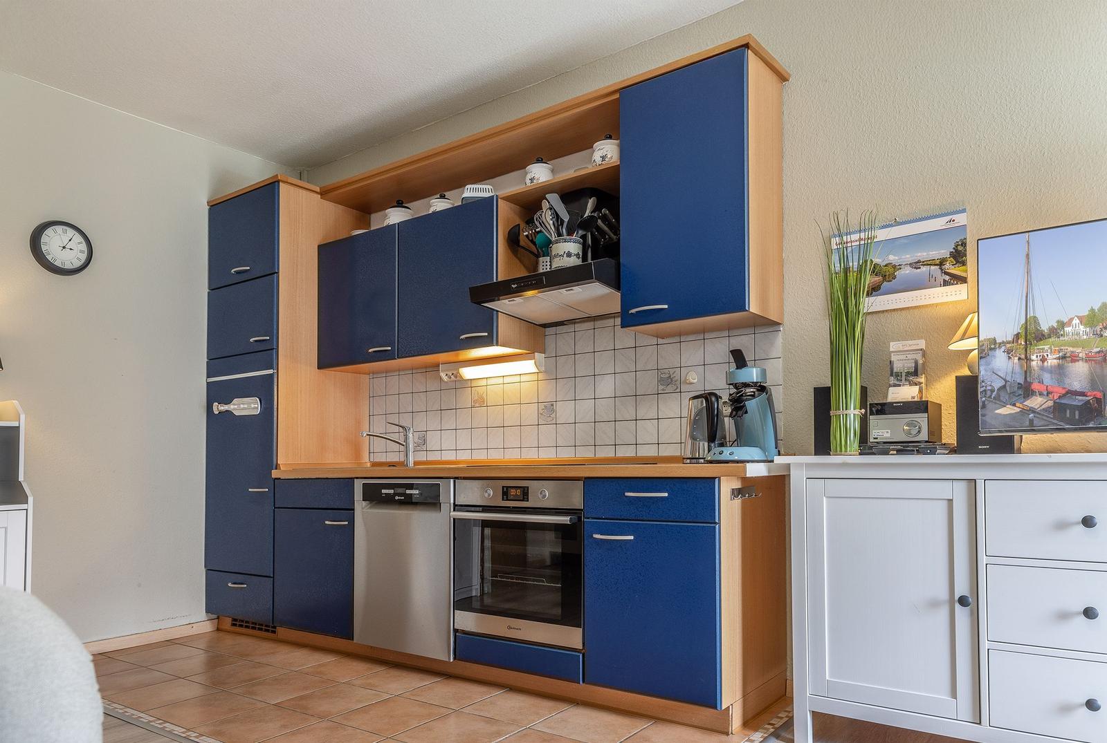 Küche mit blauen Schränken, Spüle, Herd und Kühlschrank.