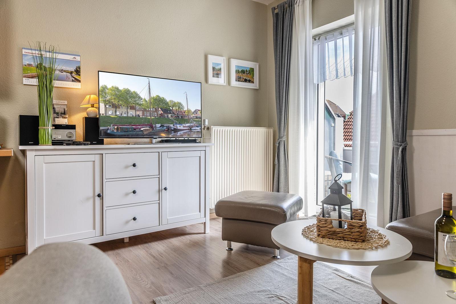 Wohnzimmer mit TV, Couch und Blick auf Balkon