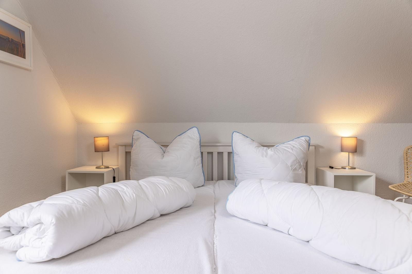 Schlafzimmer mit Doppelbett, zwei Nachttischen und Lampen.