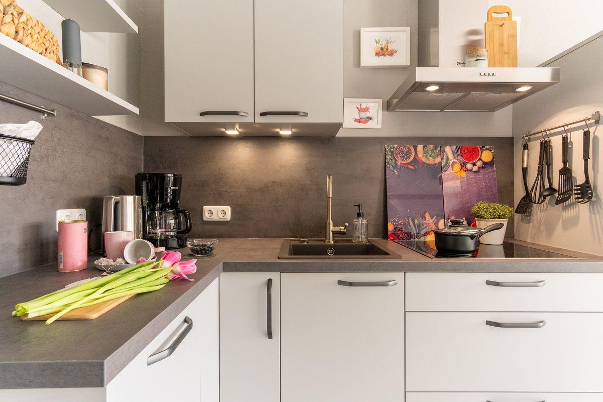 Moderne Küche mit Arbeitsplatte, Spüle und Küchenutensilien.