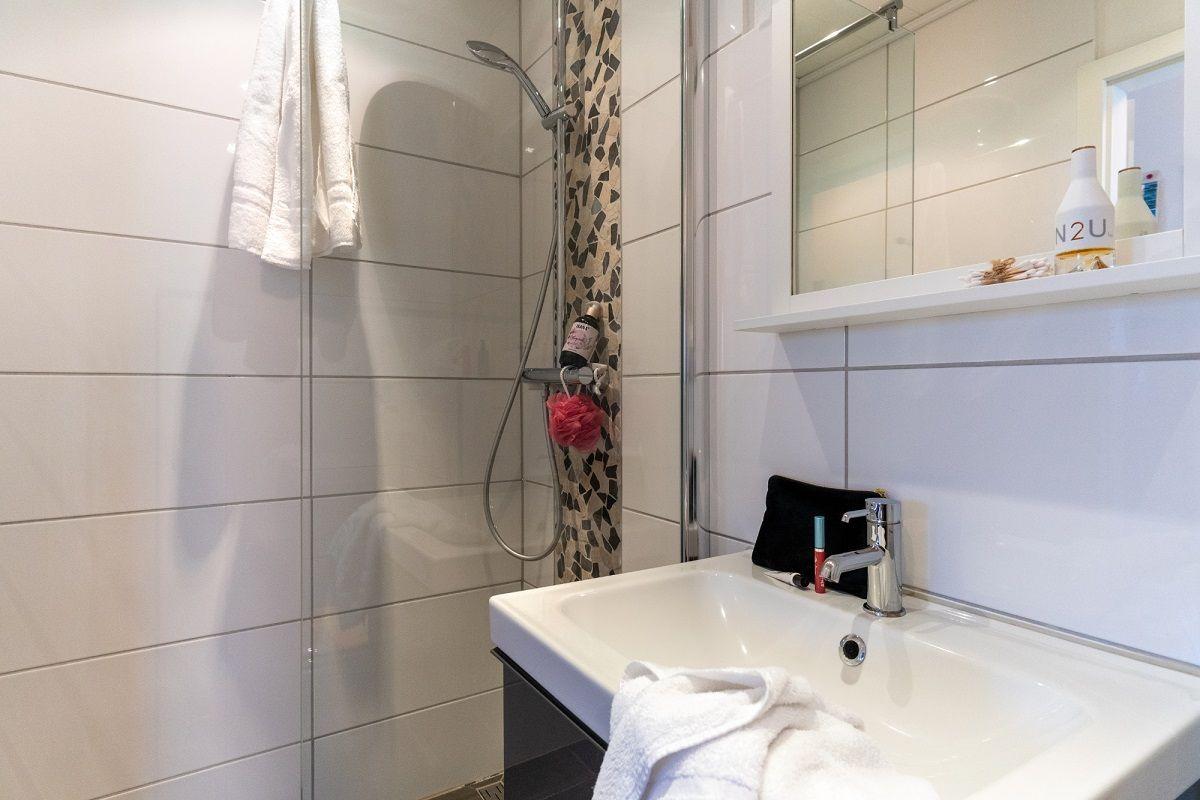 Badezimmer mit Dusche, Waschbecken und Spiegel