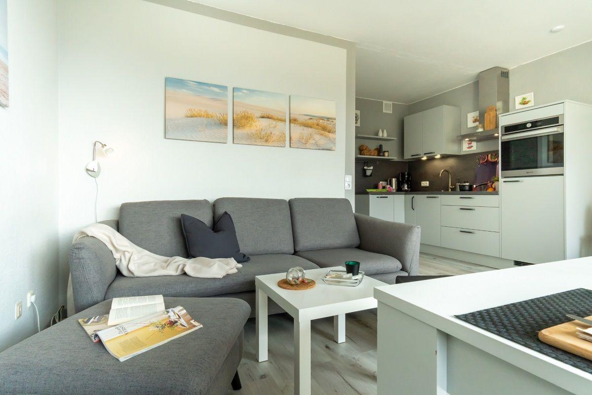 Wohnzimmer mit Sofa, Couchtisch und Küche im Hintergrund.