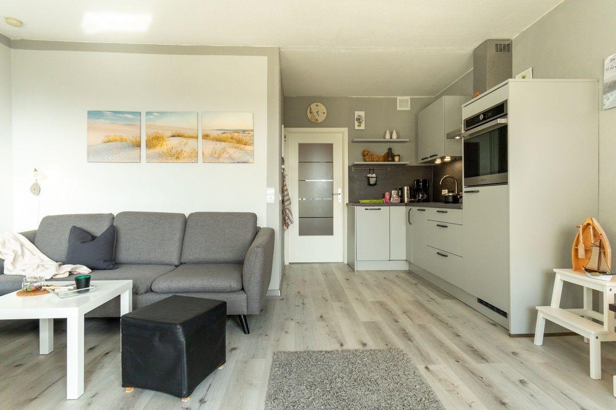 Wohnbereich mit Sofa, Couchtisch und Küche in moderner Einrichtung.