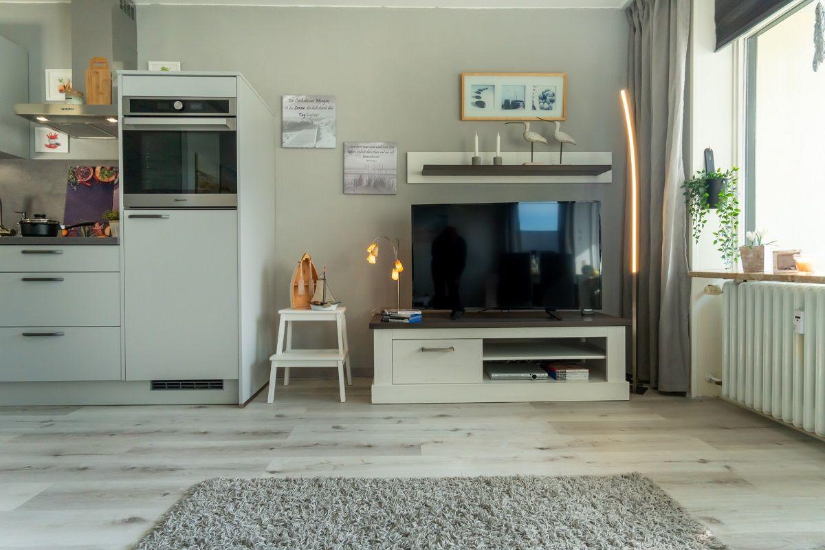 Küche und Wohnzimmer mit TV, Regal und Fenster.