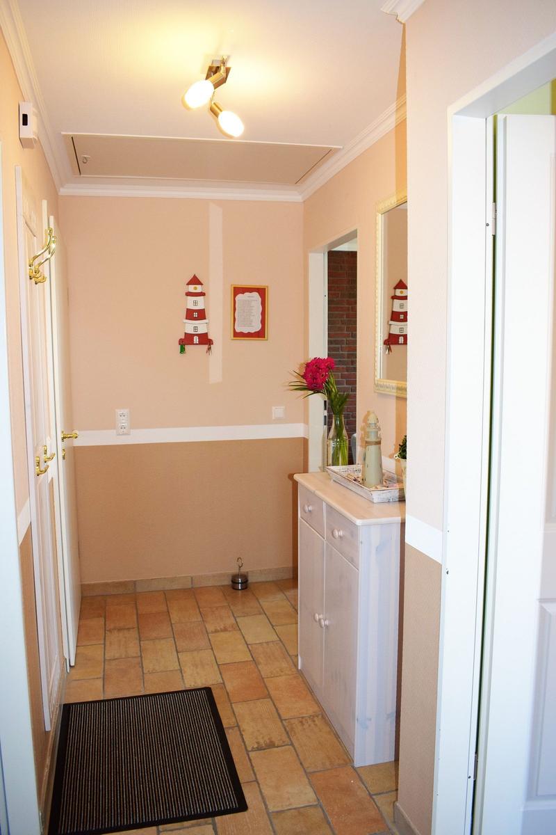 Flur mit Holzboden, Schrank und Leuchte. Wanddekoration mit Laterne.