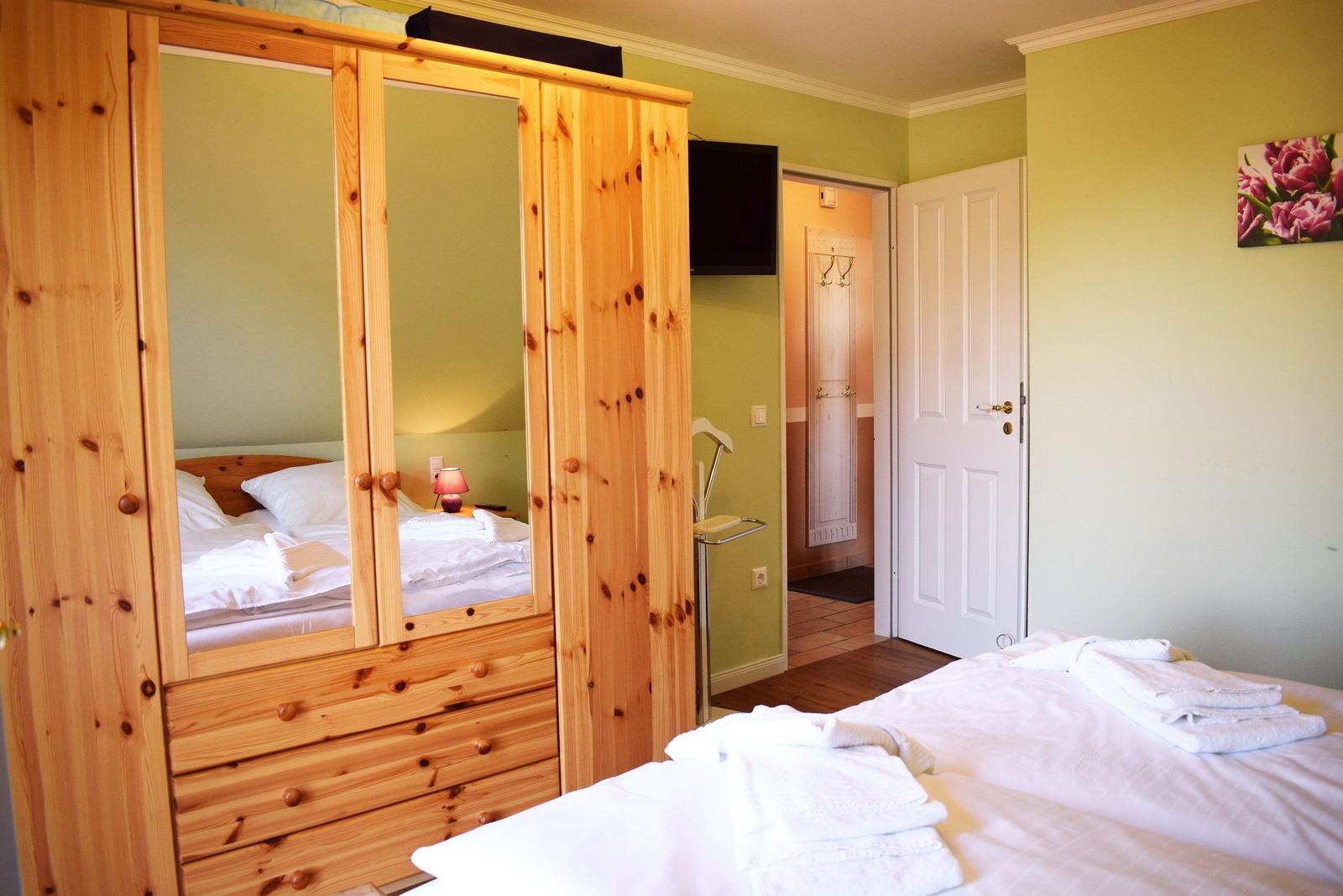 Schlafzimmer mit Holzschrank, Bett und Fernseher an der Wand.