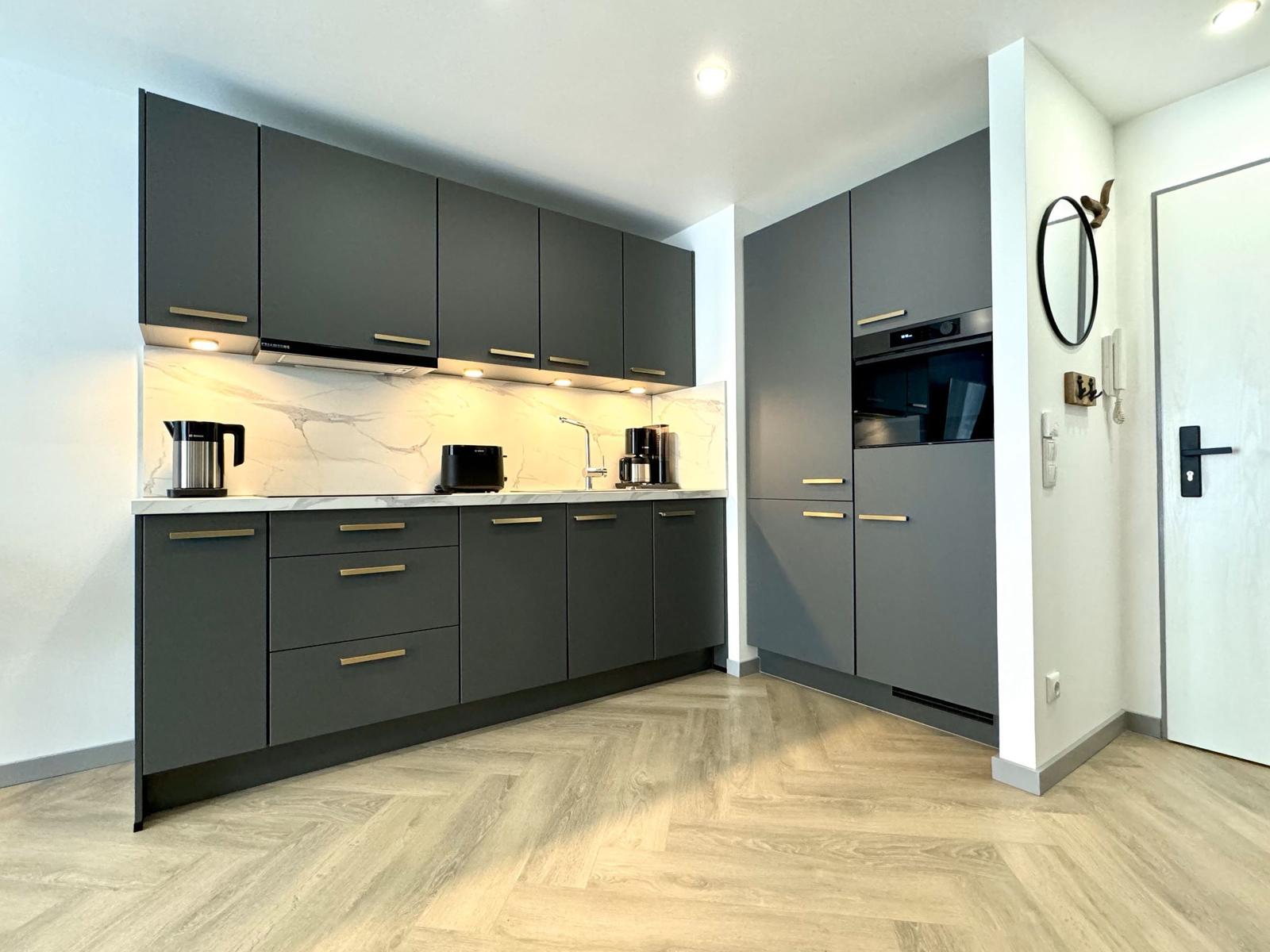 Moderne Küche mit grauen Schränken und Marmorarbeitsplatte.