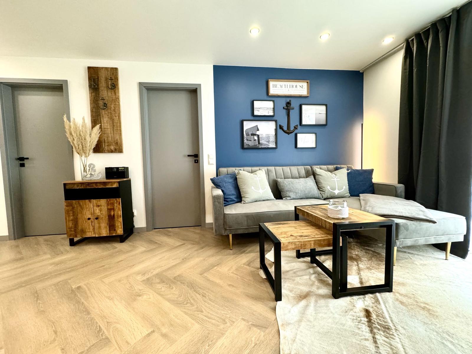 Wohnzimmer mit Sofa, Couchtisch und blauer Wand mit Bildern.