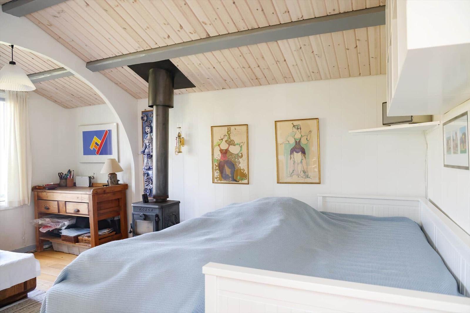 Schlafzimmer mit Bett, Kamin und Wandbildern.