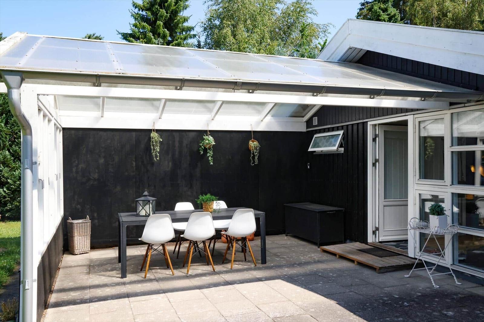 Terrasse mit Tisch, Stühlen und Pflanzen unter einer Markise.