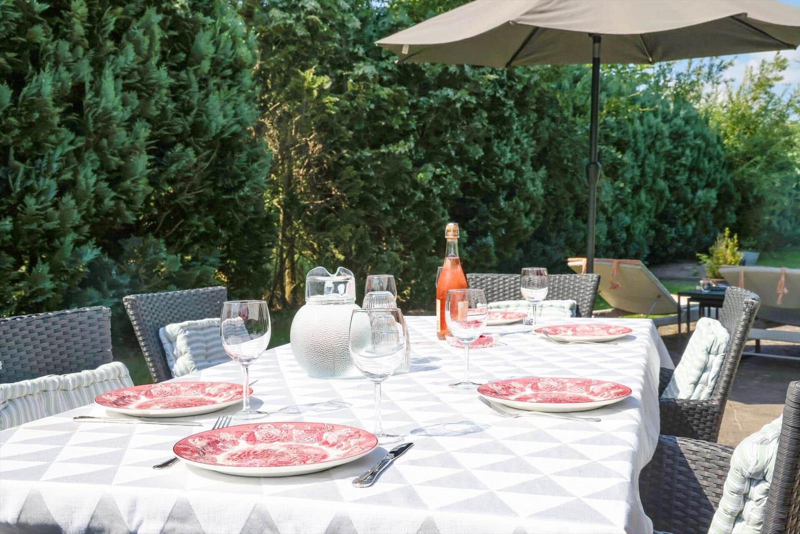 Garten-Tisch mit Platz für sechs Personen unter Sonnenschutz.