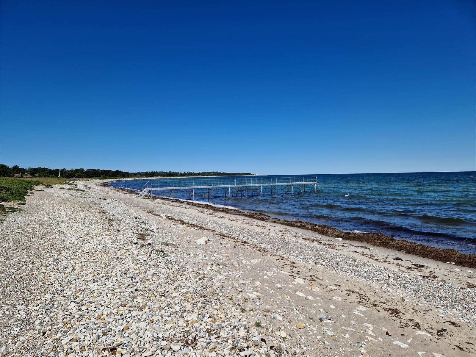 Steiniger Strand mit Steg direkt ins Wasser