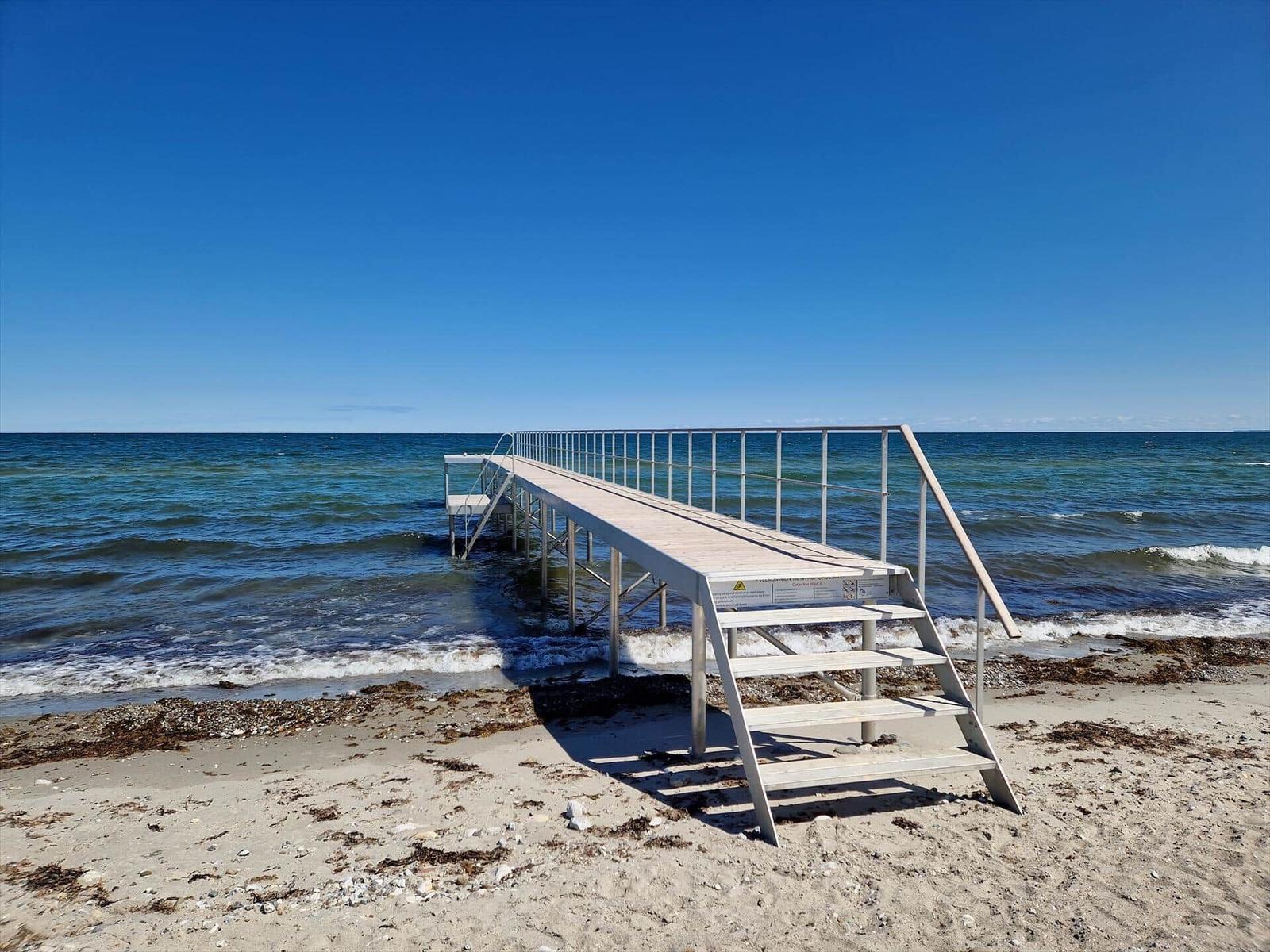Hölzerne Stegbrücke mit Leitern führt direkt ins Meer.