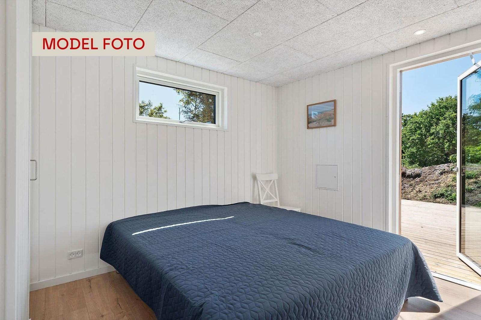 Schlafzimmer mit Bett, Fenster und Tür zur Terrasse.