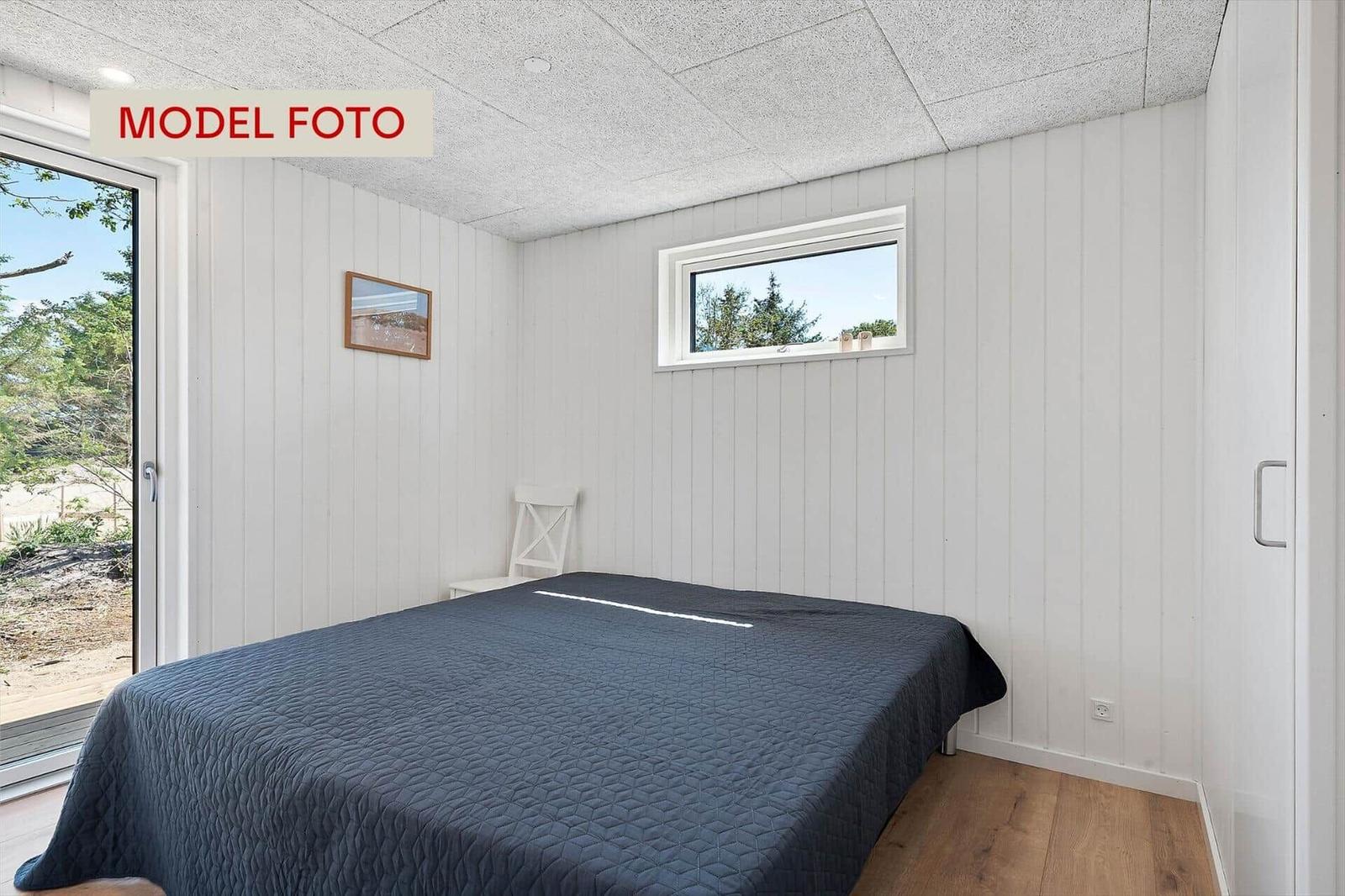 Schlafzimmer mit Bett, Fenster und Tür zur Terrasse.