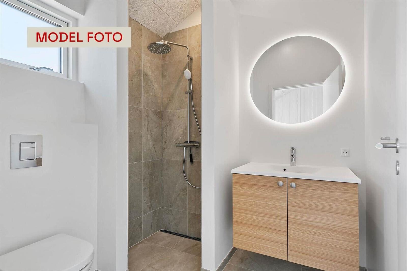 Bad mit Dusche, Waschbecken und Toilette. Runder beleuchteter Spiegel.