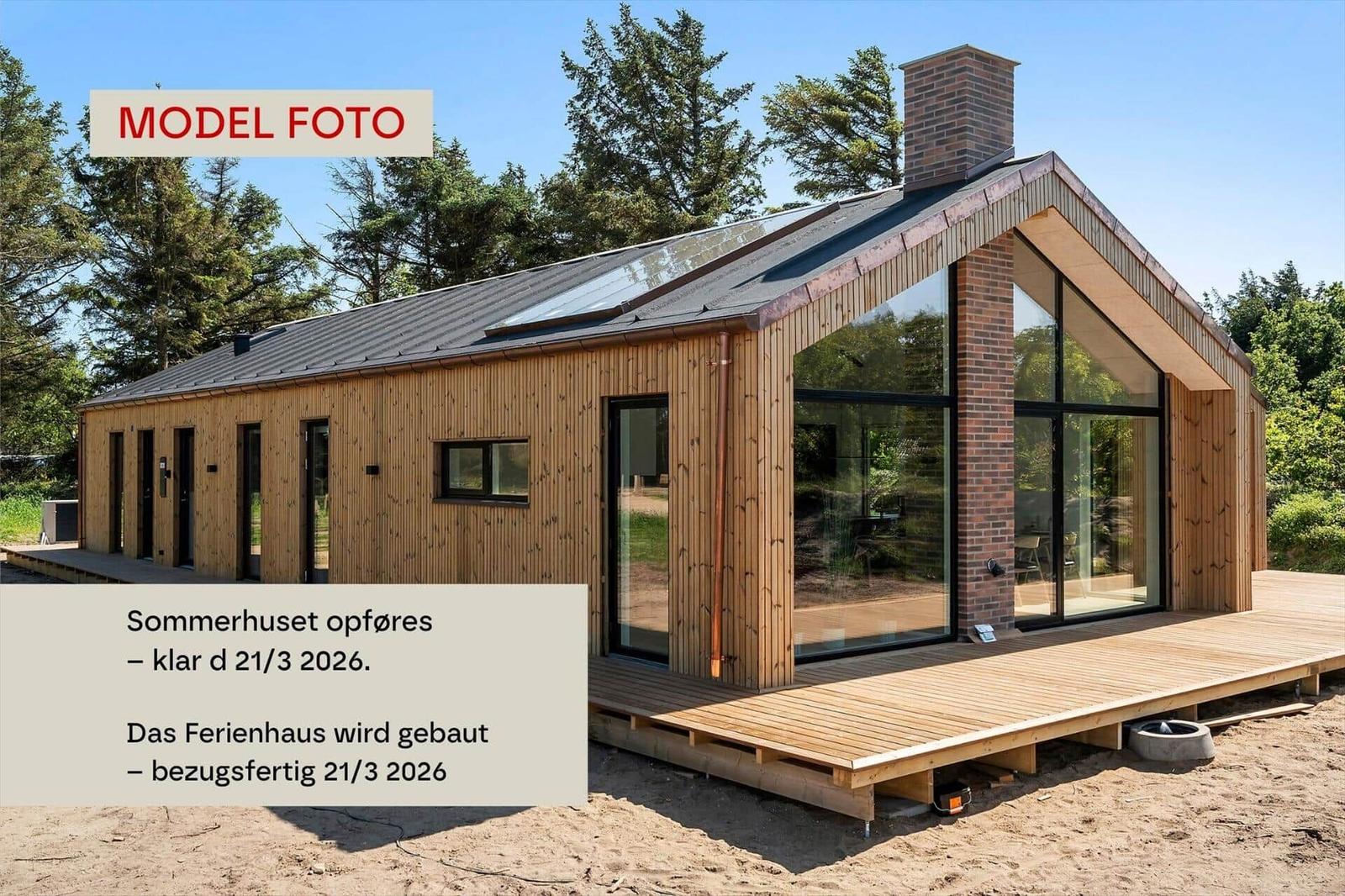 Modernes Ferienhaus mit Holzfassade und großem Glasbereich auf Holzterrasse.