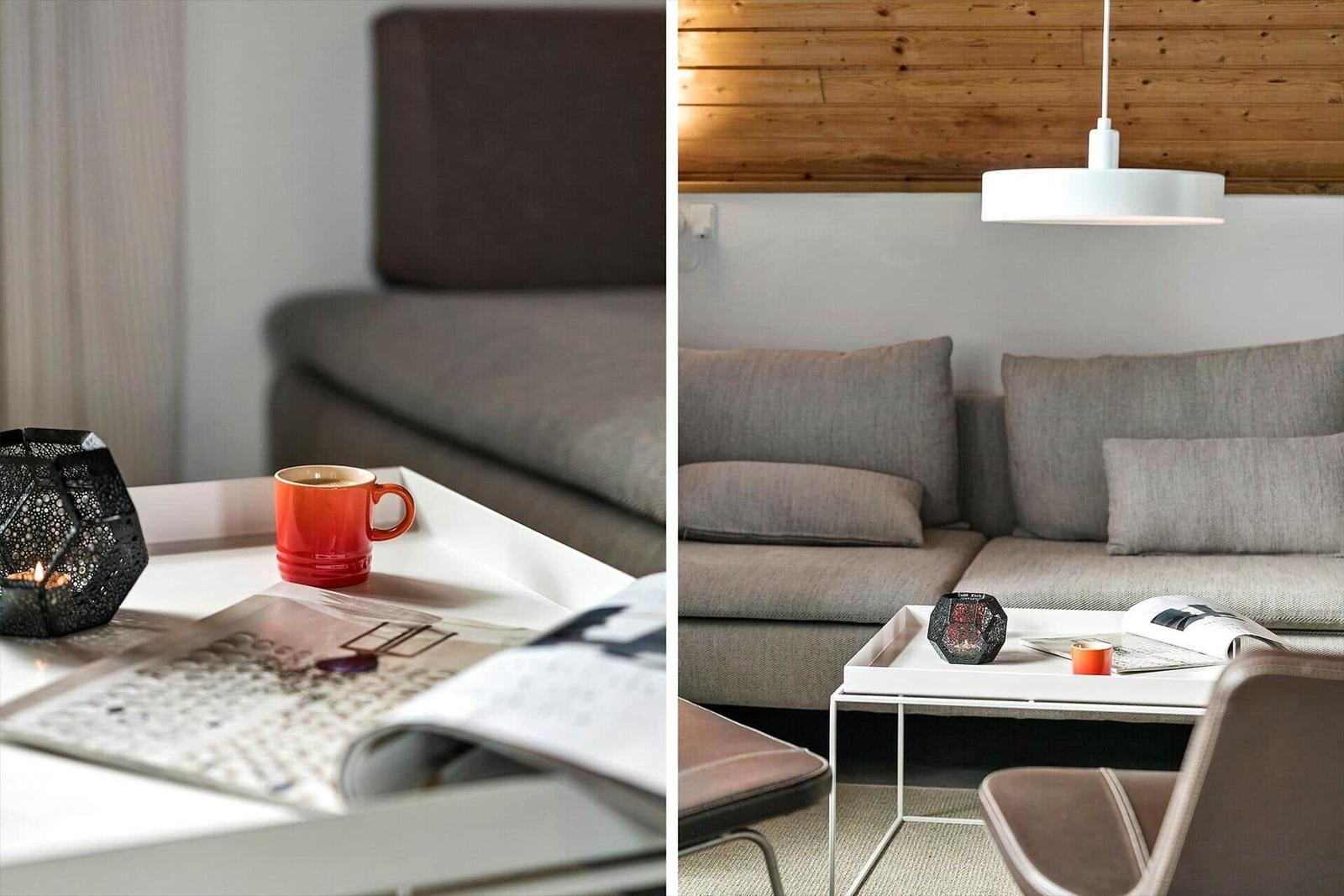 Ein Wohnbereich mit grauem Sofa, weißem Couchtisch und Holzwand.