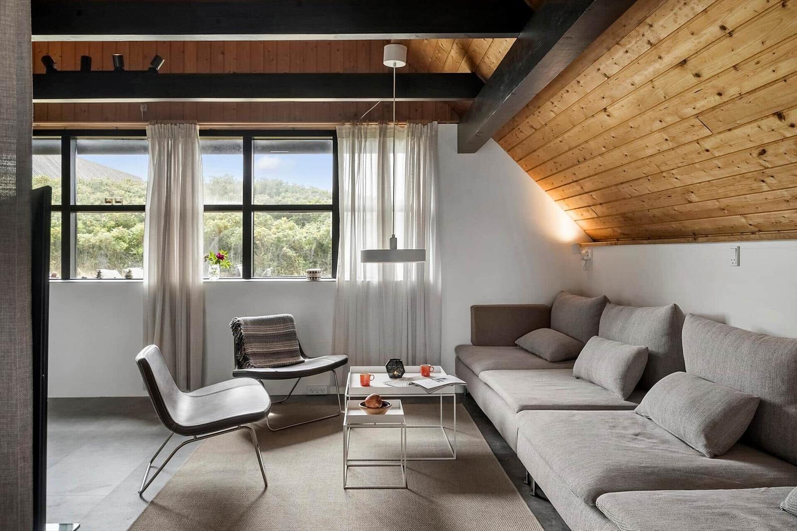 Wohnzimmer mit Sofa, Stühlen und Blick auf Grünflächen.